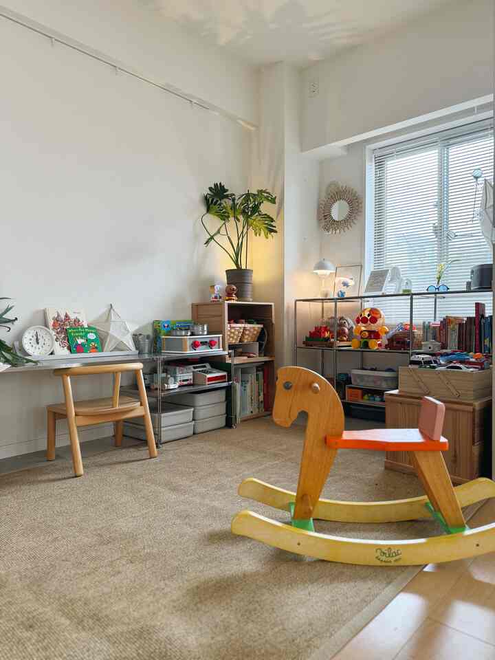ナチュラルカラーと木目調が調和した子供部屋、おもちゃ収納棚と木製のロッキングホースが配置された温かみのあるインテリア