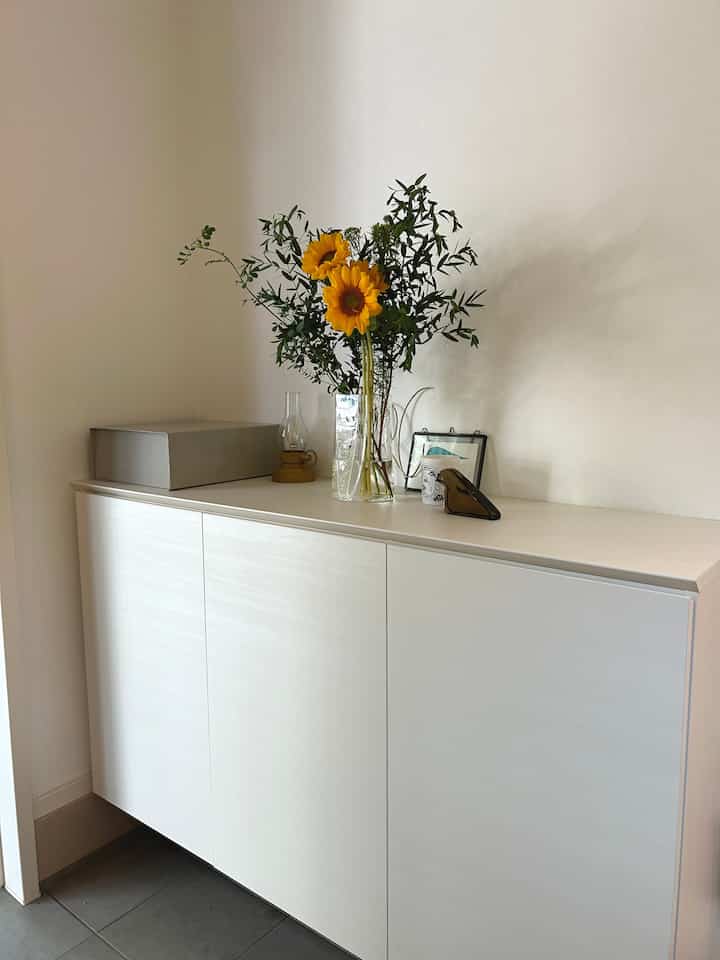 白を基調とした玄関、シューズラックの上にひまわりと植物が配置された清潔感のある空間