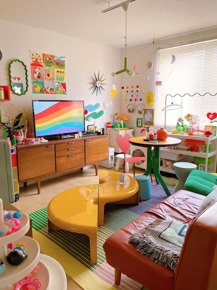 カラフルなリビングルーム、黄色いコーヒーテーブルと茶色のソファ、緑のペンダントライトが調和した印象的な空間