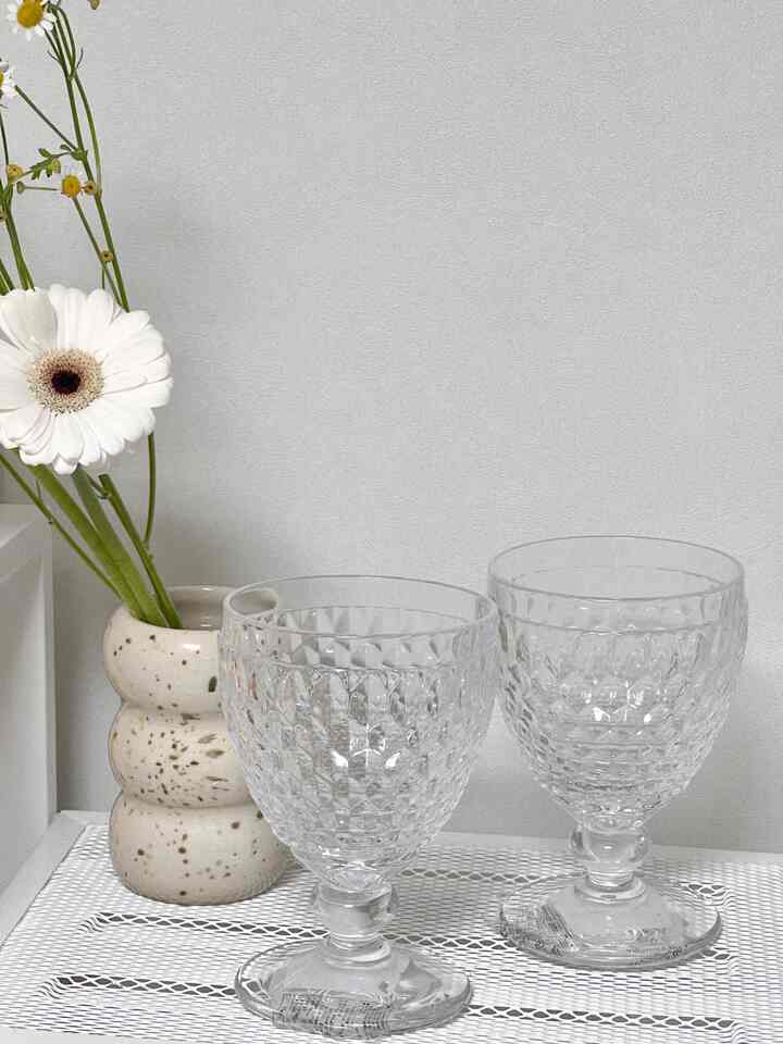 White-walled, simple kitchen space featuring two textured transparent goblets and a unique ceramic vase with flowers creating an elegant interior