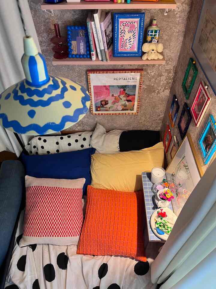 カラフルなクッションとアートが配置された、居心地の良い寝室のインテリア