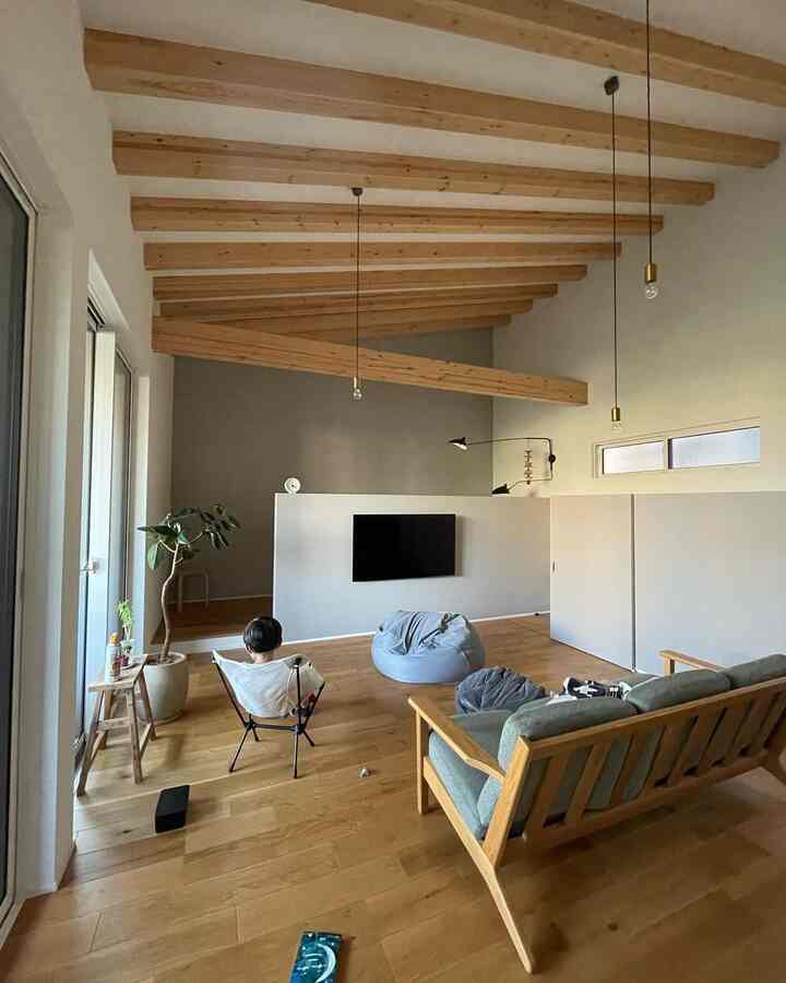 ナチュラルな木目調とあらわし梁が印象的なリビング、ビーズクッションとヘリノックスチェアが配置された雰囲気のある空間