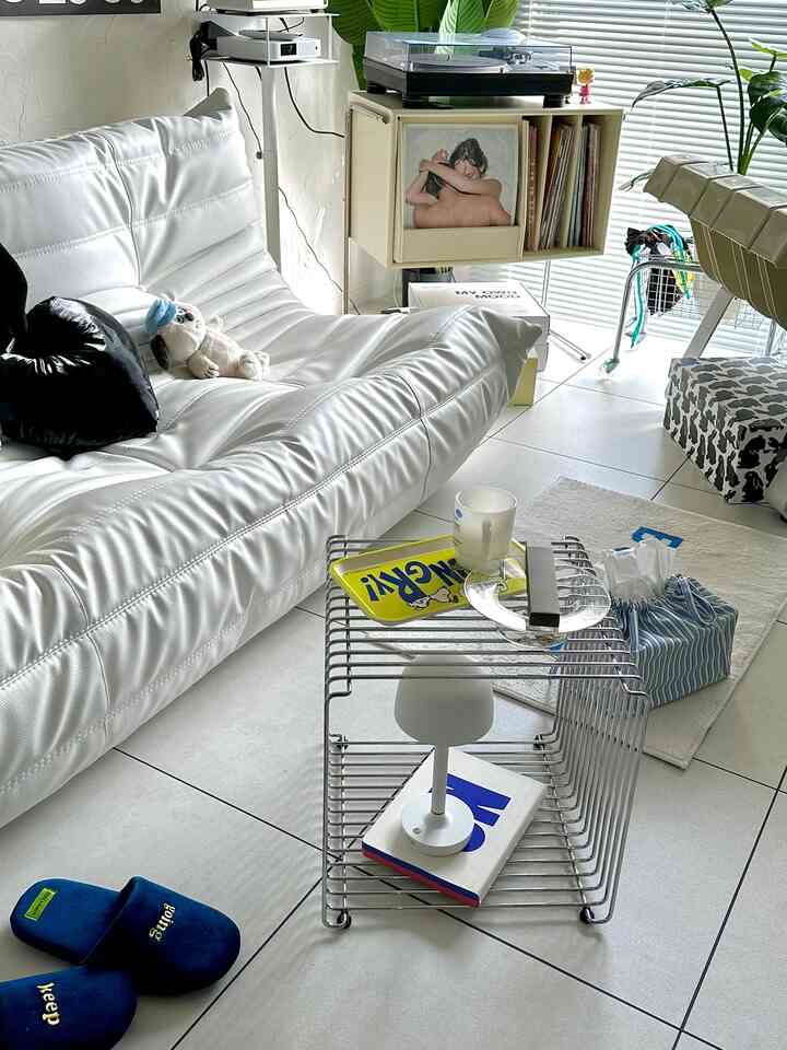 ホワイトトーンのリビング、モダンなホワイトソファとワイヤーメタルのサイドテーブルが配置されたシンプルな空間