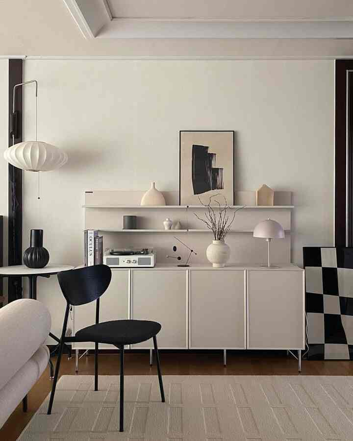 白と黒の調和が美しいモダンなリビングルーム、大型収納キャビネットとラグ、多彩な小物が配された洗練された空間