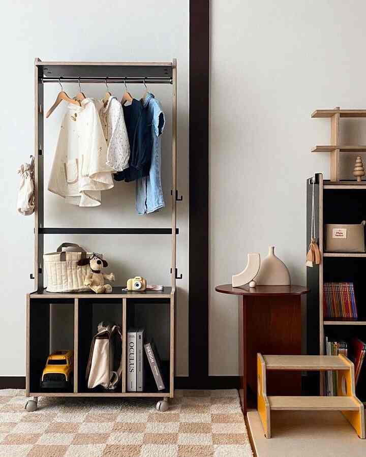 ナチュラルな木目調とベージュ色のリビング、整理されたハンガーと本棚が配置された雰囲気のあるインテリア