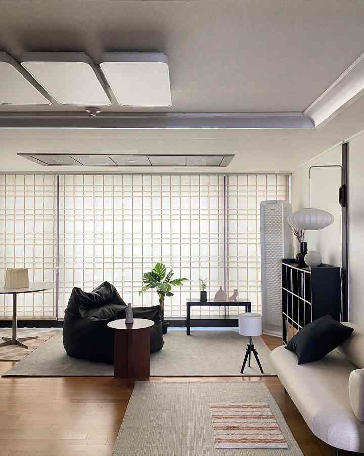 ナチュラルカラーとブラックが調和するリビング、広いビーズクッションとシンプルなソファが配置されたミニマルな空間