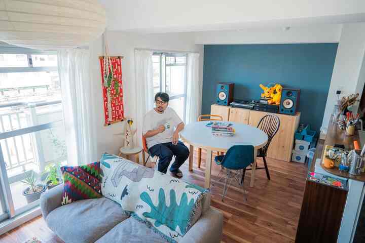 ホワイトとブルーの色調のリビング、ナチュラルウッドの家具と多様な椅子が配置された雰囲気のある空間