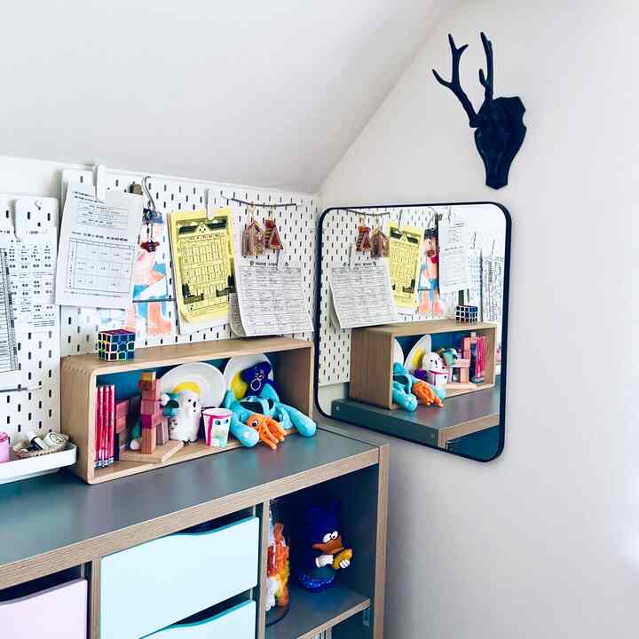 Children's room with white walls and natural wood furniture, featuring bookshelf, mirror, and wall decor creating a harmonious space