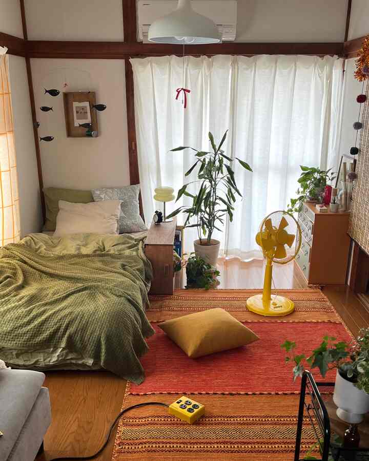 Natural beige and green toned bedroom featuring bed and various plants, cozy single household space