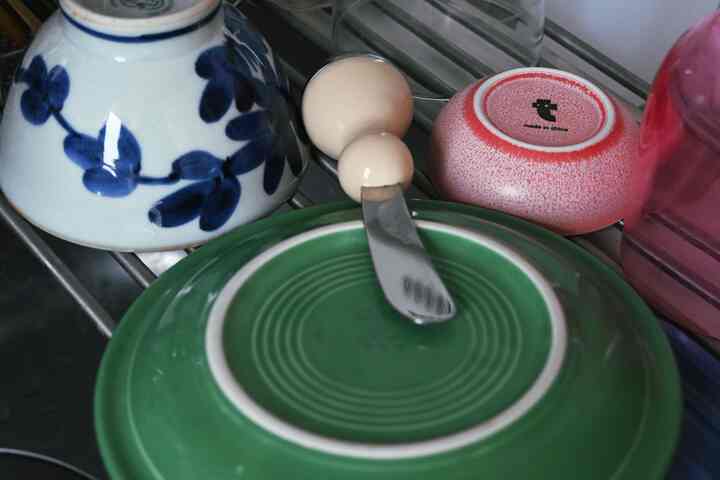 緑の皿と青い模様の白い器が並ぶキッチンのカラフルな洗った食器