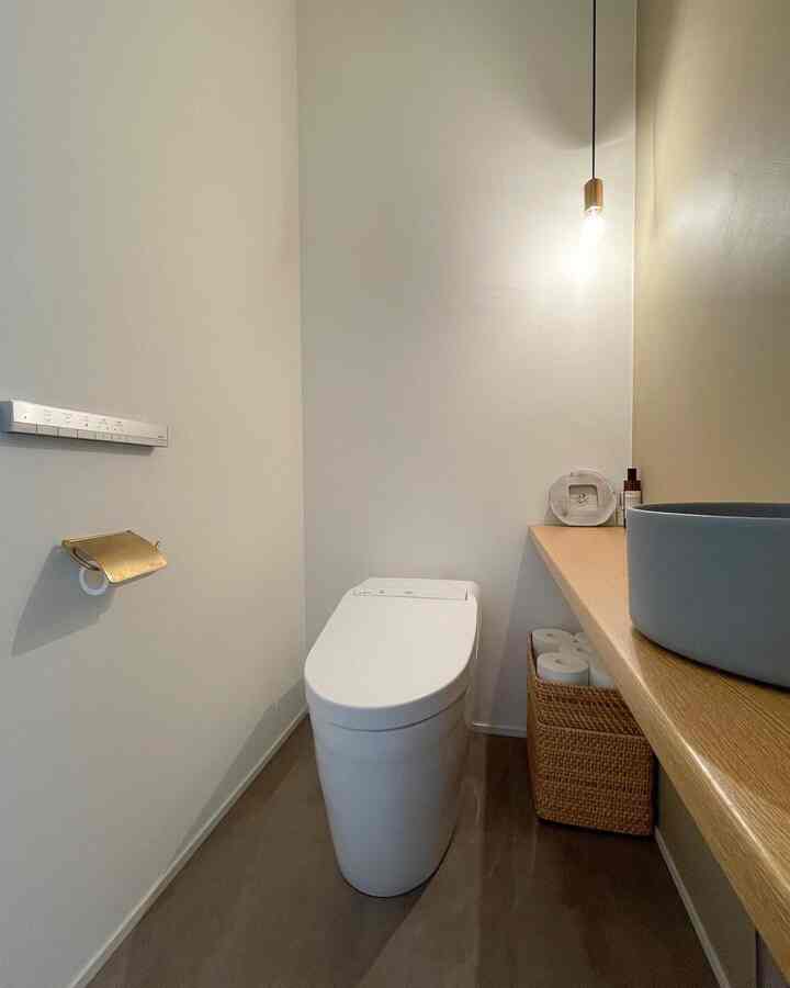 白と木目調が調和したシンプルでモダンなバスルーム、埋め込み式トイレとペンダントライトが配置された空間