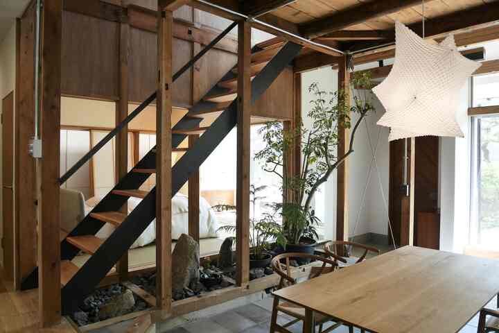 Natural wood tone dining corner under stairs with green plants and a subtle Japanese style ambiance