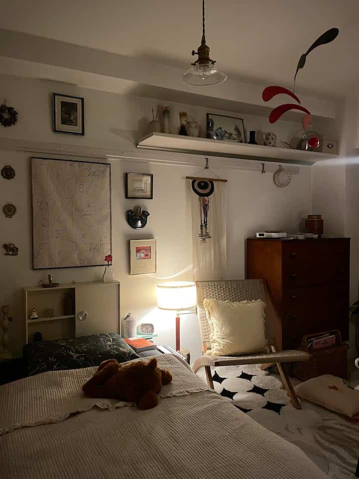 白と茶色のトーンの寝室、ベッドとアームチェアが配置された雰囲気のあるヴィンテージ空間