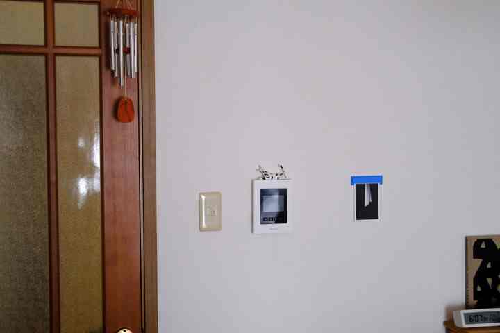 ナチュラルな木目調の玄関、扉横にウッドウィンドチャイムが掛かり、白い壁がシンプルな雰囲気を醸し出すインテリア