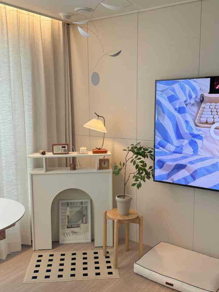 温かみのある木目調と白を基調としたリビング、シンプルモダンなスタイルでペットベッドと植物が配置された空間