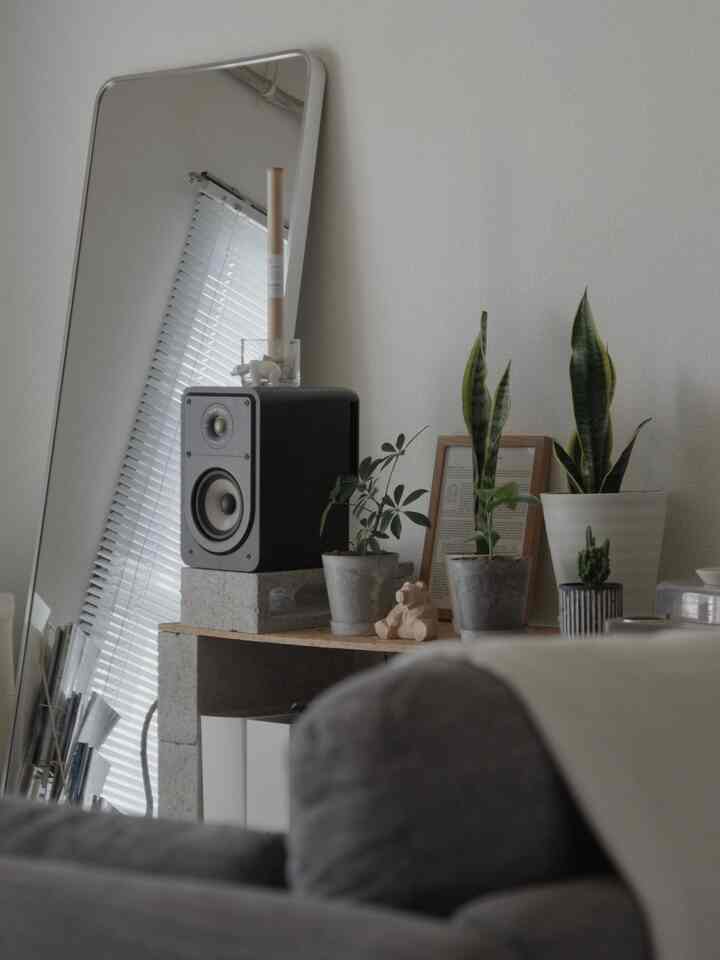 白い壁とグレーのソファがあるナチュラルモダンなリビング、コーナーにコンクリートブロックの収納と多くの植物が配置された空間