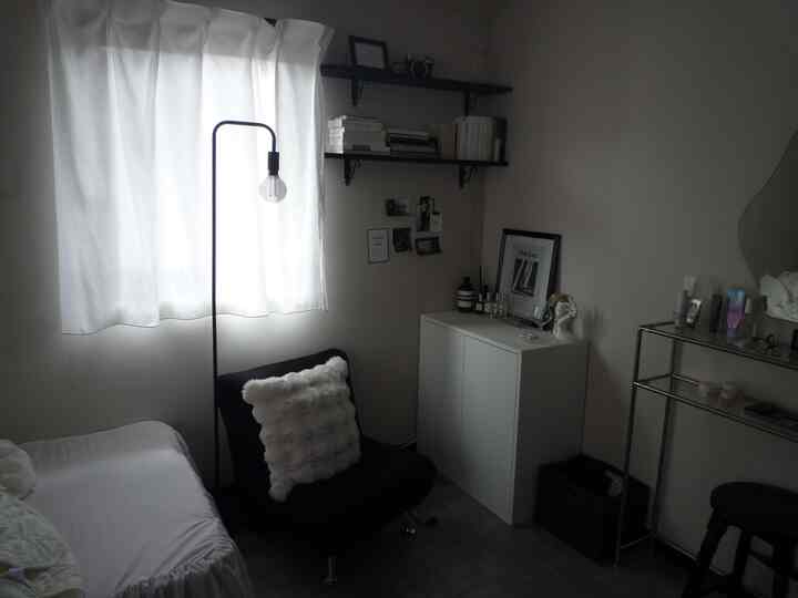 白と黒の調和が取れた小さなリビング、黒のアームチェアとフロアランプが置かれたシンプルな空間