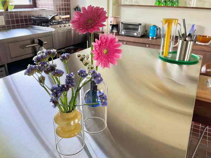 ナチュラルカラーとステンレス素材の調和がとれたキッチン、花瓶とトレイが配置された清潔感のある調理スペース