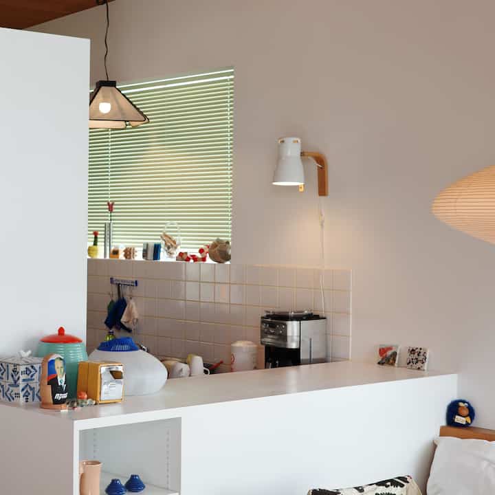 白を基調としたキッチンとダイニングの空間、コーヒーメーカーとペンダントライトが配置されたモダンで清潔感のあるインテリア