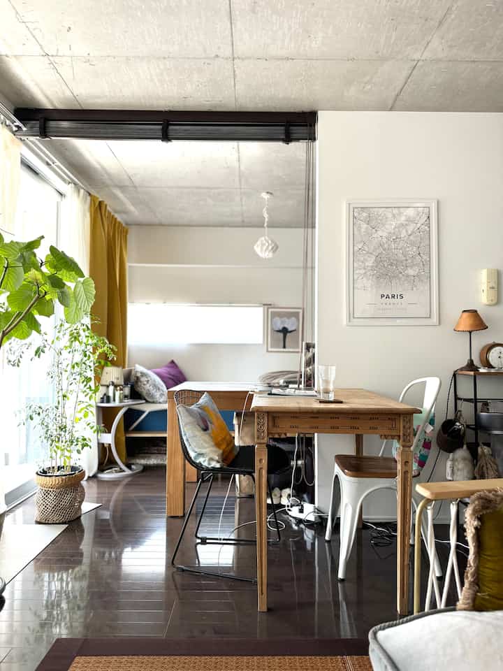 Wood tone and yellow curtain accented living room featuring a French Country style wooden table and mixed chairs creating a cozy atmosphere