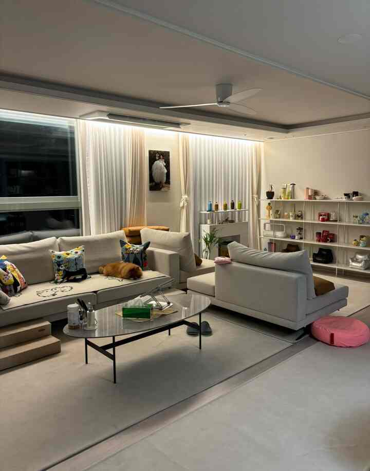 Bright white and beige toned wide living room featuring a large modular sofa and neat decor creating a cozy atmosphere