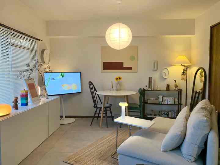 Bright white-toned living room featuring beige sofa and round dining table with a natural, cozy atmosphere