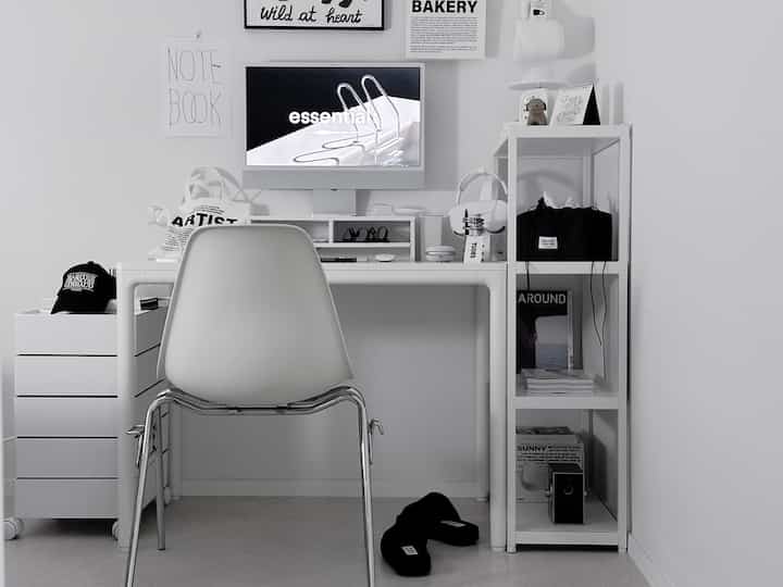 Monotone white and black study space featuring a compact desk, chair, and bookshelf with a clean and focused atmosphere