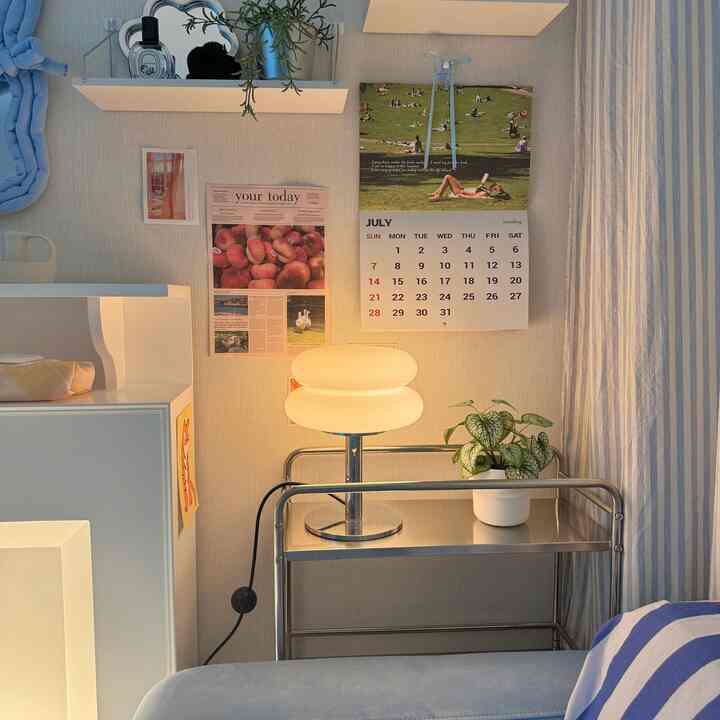 Sky blue and beige toned bedroom featuring a mid-century modern table lamp and a potted plant, creating a cozy atmosphere