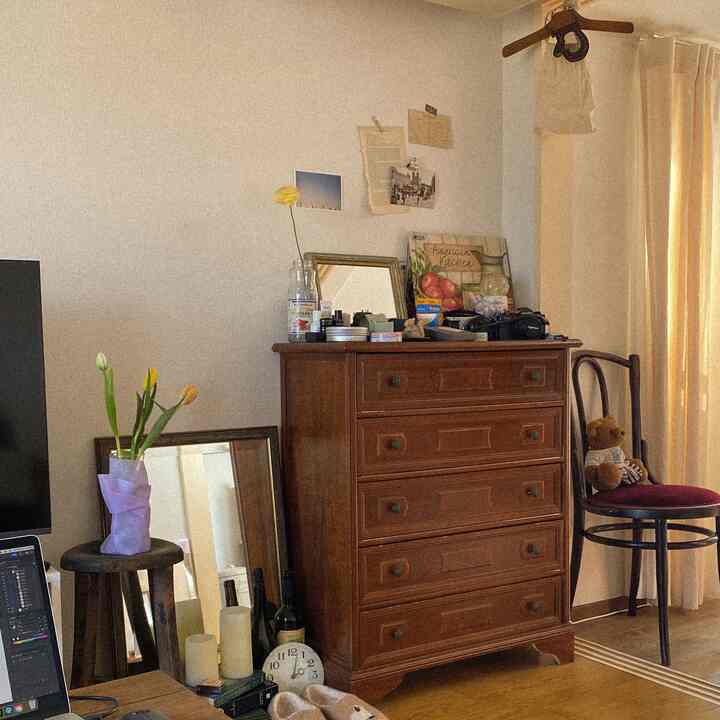 ブラウンの木目調が特徴的な一人暮らしの部屋、ヴィンテージスタイルのチェストとベントウッドチェアが配置された雰囲気のある寝室