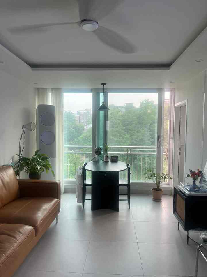 ブラウンレザーのソファと黒く塗られたダイニングテーブルが配置されたリビング、窓の外に緑あふれる森の眺めが広がる落ち着いた空間