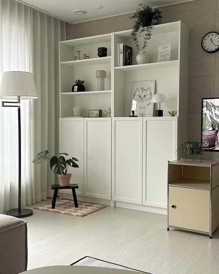 明るい白とナチュラルトーンのリビング、植物とフロアランプが配置されたシンプルモダンなインテリア