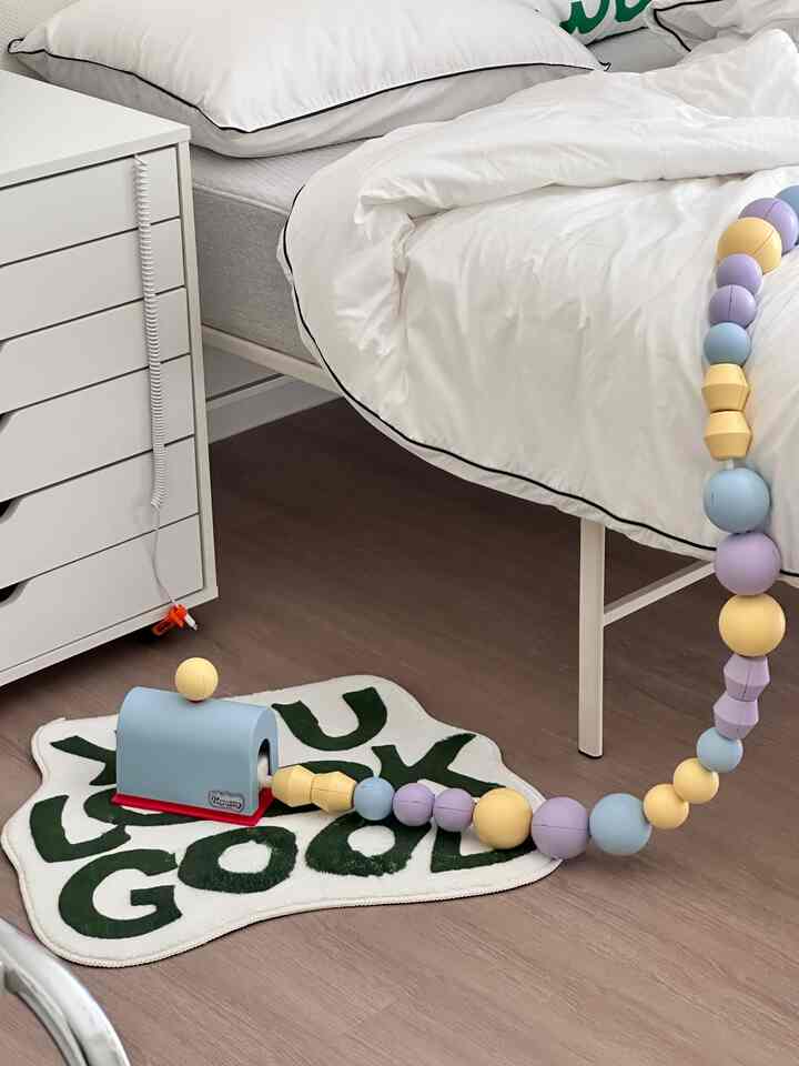 White-toned bedroom featuring a white bed and dresser with baby toys, creating a clean and minimal atmosphere