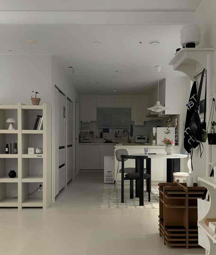 ホワイトトーンのモダンでコンパクトなキッチン、ダイニングテーブルとミニマルな家具が配置された雰囲気のあるインテリア