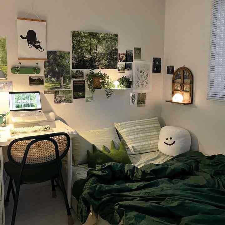 緑色の寝室、デスクと椅子、快適な布団とクッション、壁にポスターと植物が配置された雰囲気のあるインテリア