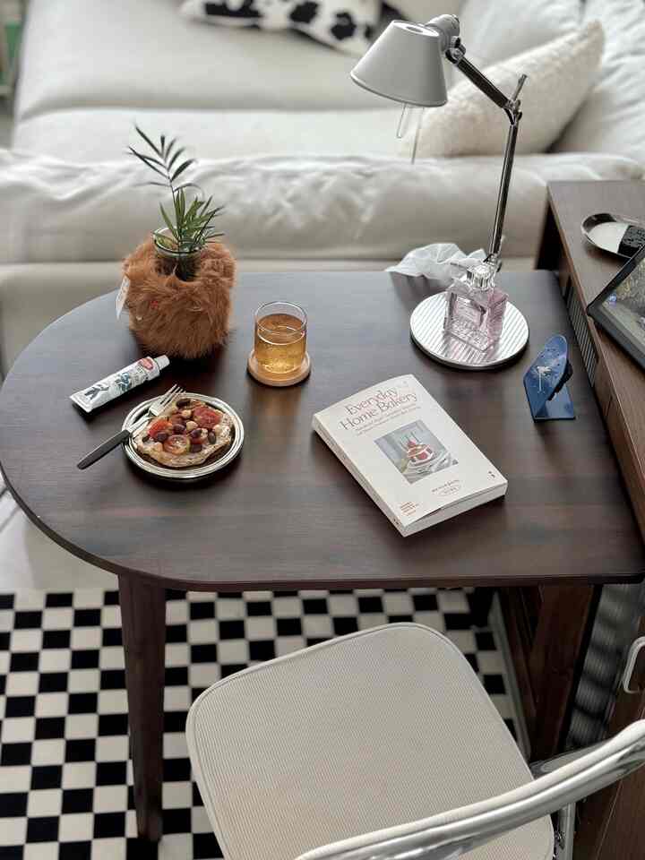 ダークブラウンの木製デスクとベージュのオフィスチェアがある落ち着いたホームオフィス、テーブルランプと本、装飾品が整然と配置された雰囲気のあるインテリア