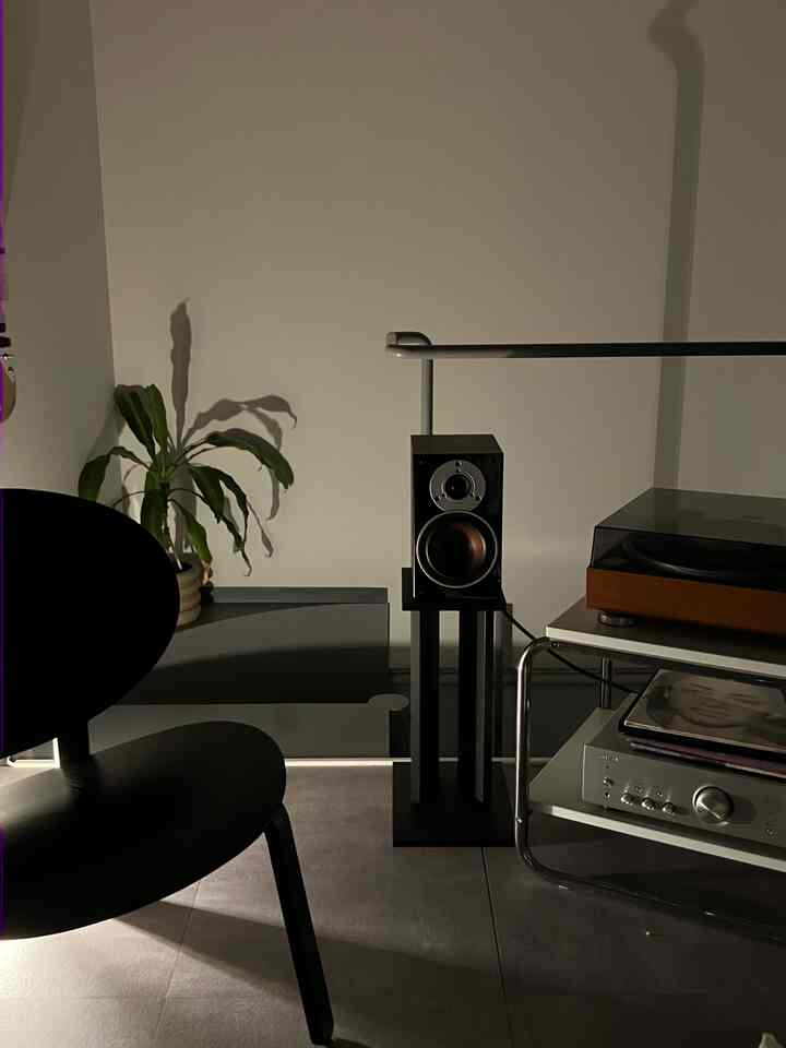 暗めの照明が落ち着いたモダンな空間、中央にスピーカーとウッド調のレコードプレーヤーが配置された印象的なインテリア