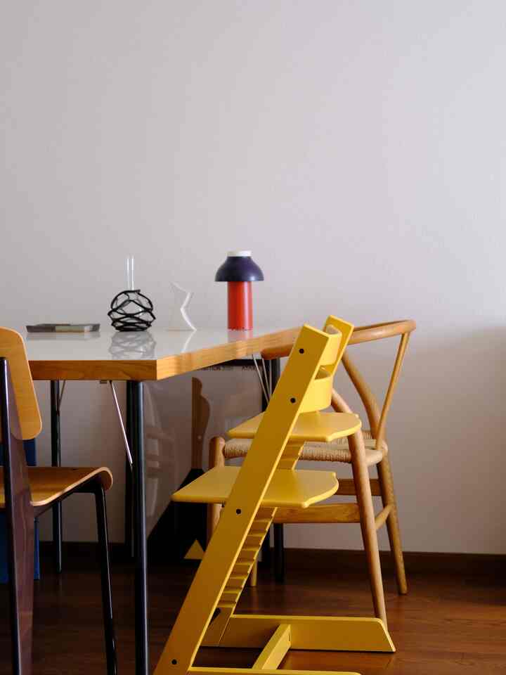 温かみのある木目調と黄色が調和したダイニングルーム、目を引く黄色のトリップトラップ子供用チェアが配置された自然なインテリア