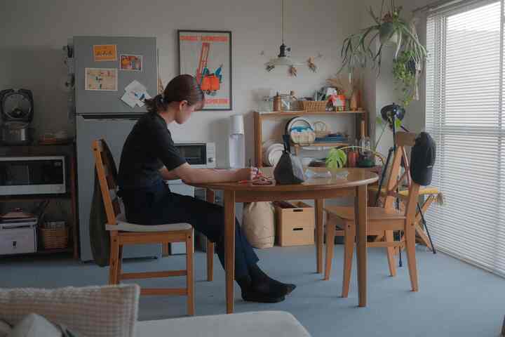 ナチュラルな色調のワンルームダイニング、木製のダイニングテーブルと椅子、ブラインド付きの窓、植物が配置された雰囲気のある空間