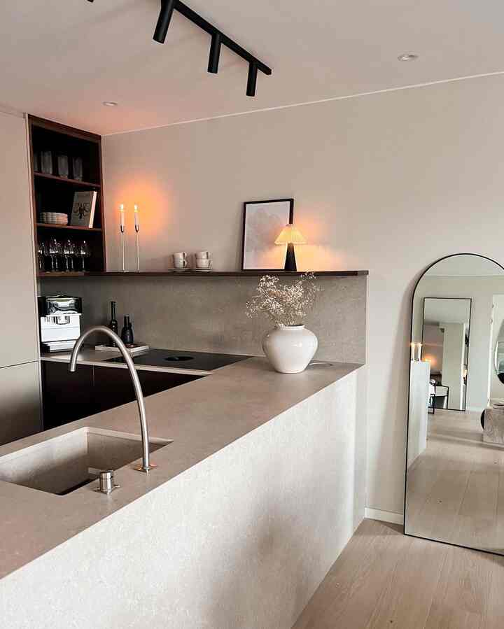 Natural-toned kitchen space featuring a kitchen island, large standing mirror, and warm lighting in a modern interior