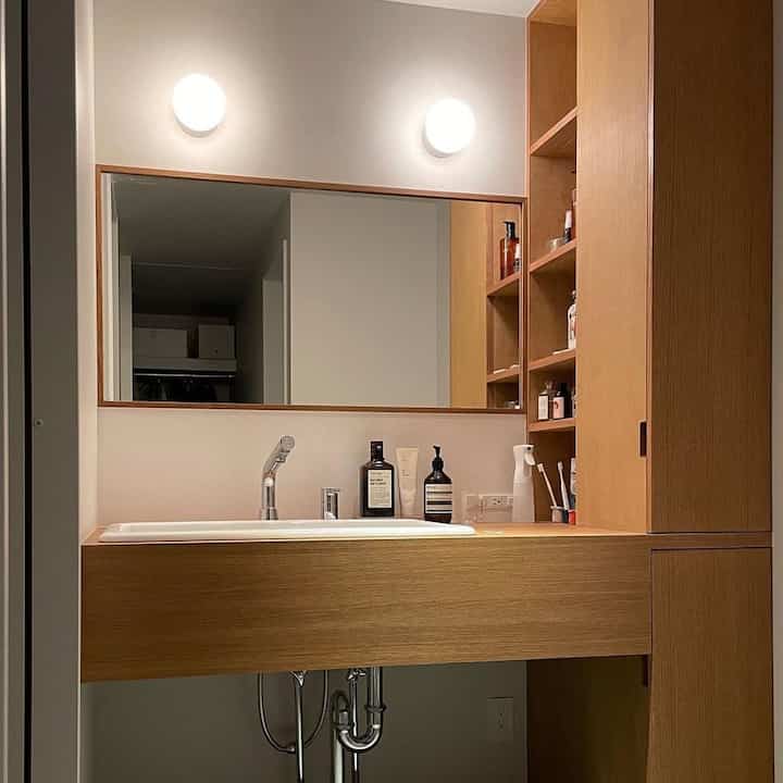 Bathroom with natural wood tones and white, featuring clean, storage-focused design