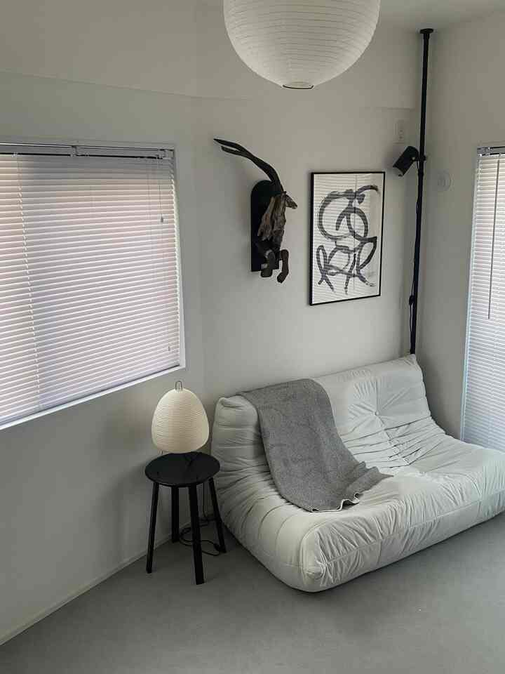 Monotone living room in white and black tones featuring a white sofa, blinds, wall-mounted animal sculpture, and modern art for a clean, stylish interior