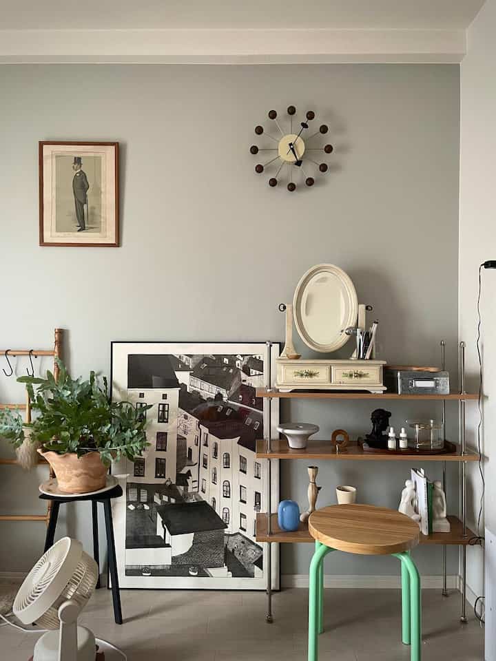 Gray-walled single household vintage-style room featuring shelves, a stool, and plants in a natural color tone
