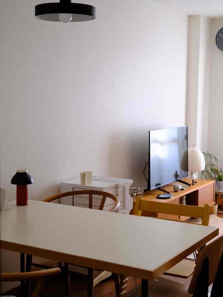 ホワイトとブラウンのトーンが調和した北欧風リビング、ダイニングテーブルとテレビ台が配置された落ち着いた空間