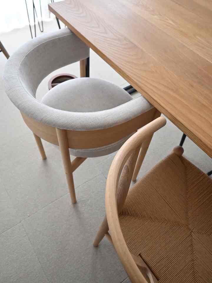 自然な木目調とグレーの色調が調和したダイニング、シンプルでモダンな印象のテーブルと椅子が配置された空間