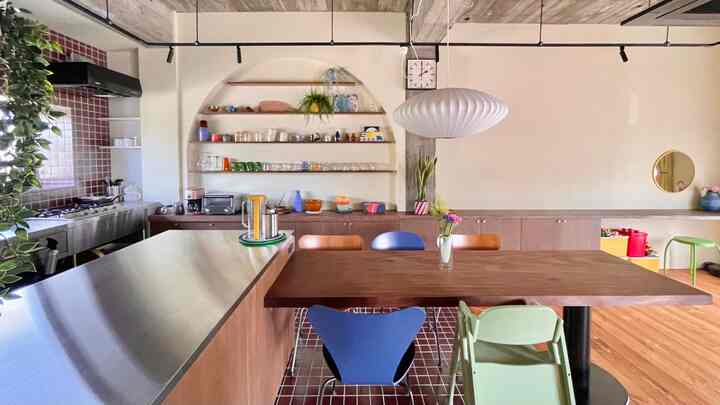 White and brown toned dining room and kitchen featuring mid-century modern dining table and chairs with pendant lighting in a cozy atmosphere