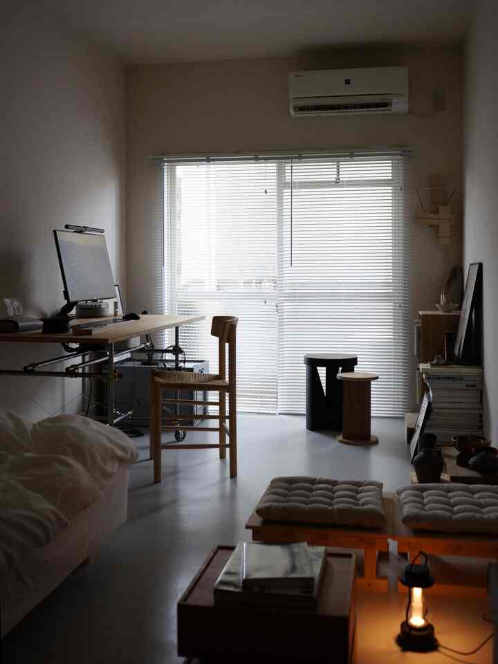 明るい白とナチュラルトーンのホームオフィス、ソファと机が配置された落ち着いた印象の空間