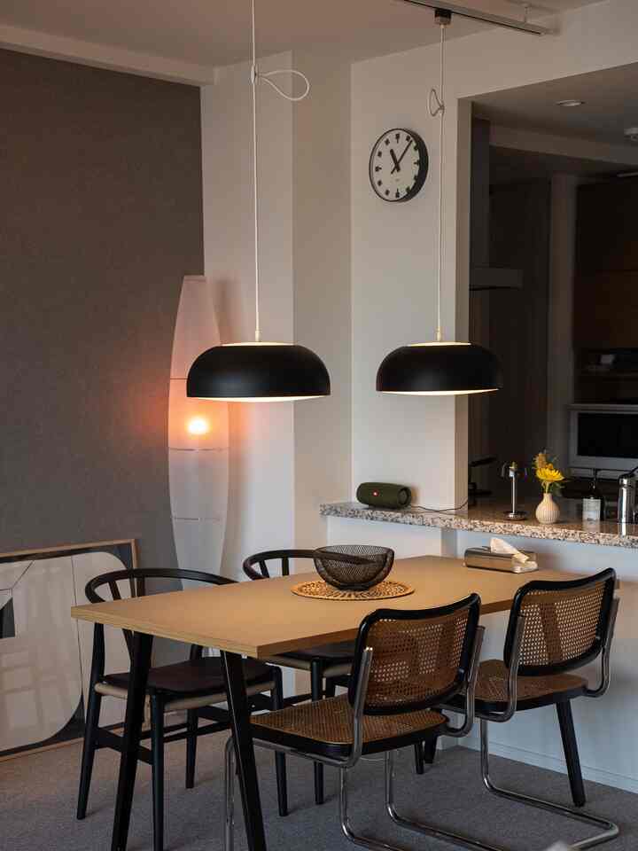 Natural tones and black accents define the dining room, centered around a dining table and chairs creating a cozy atmosphere