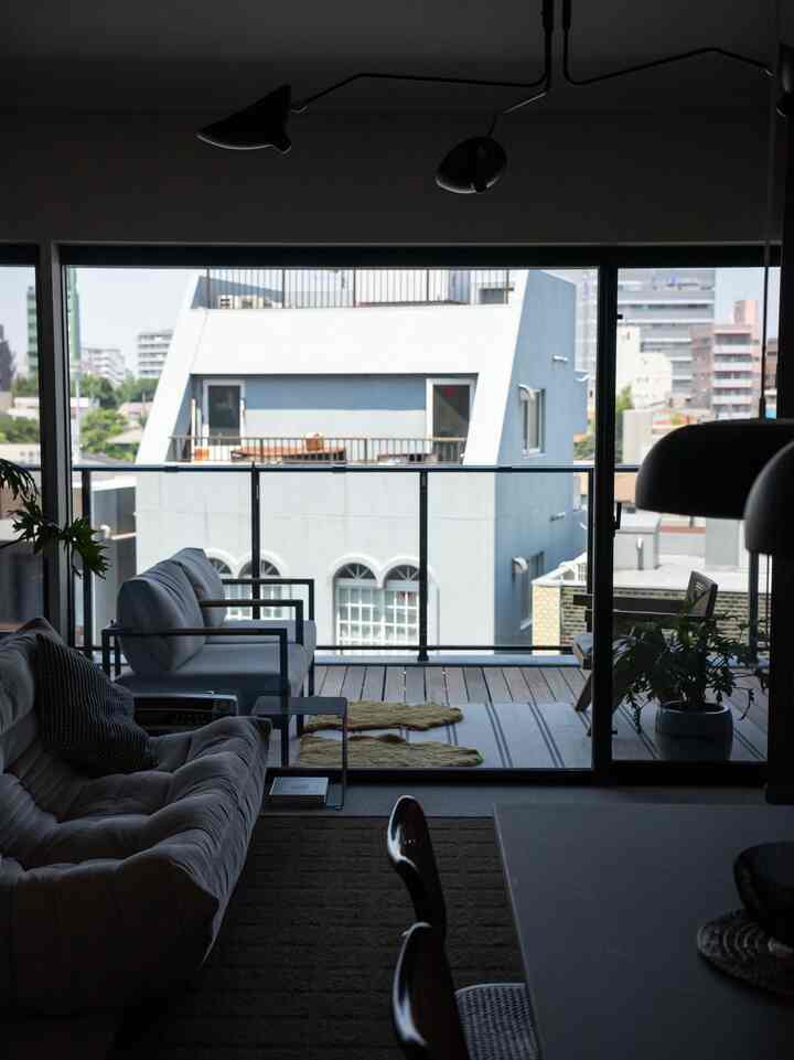 グレーと白のトーンのリビングとバルコニーが大きなガラス窓で繋がり、ゆったりとしたモダンな雰囲気のインテリア