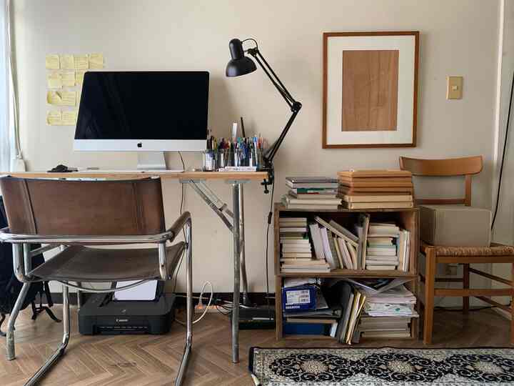 ナチュラルな色調のワークスペース、机にコンピューターと照明が配置された温かみのあるインテリア