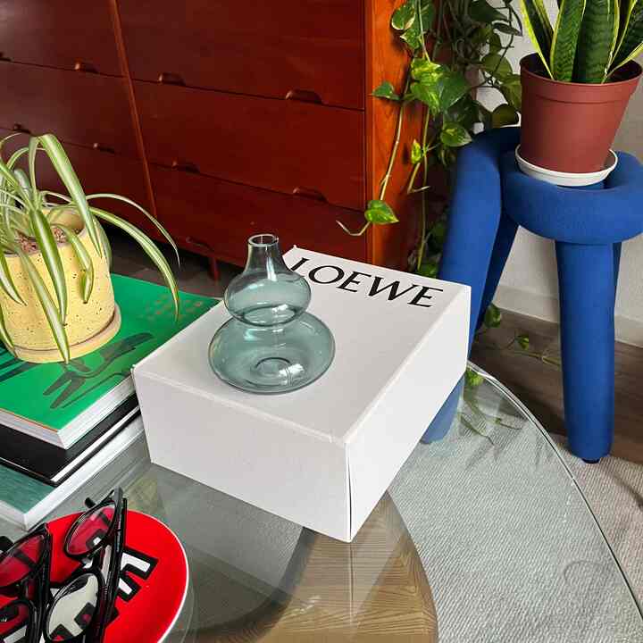 パステル調のリビング、ガラスの花瓶とプラントスタンド、木製の引き出しが配置された雰囲気のあるインテリア